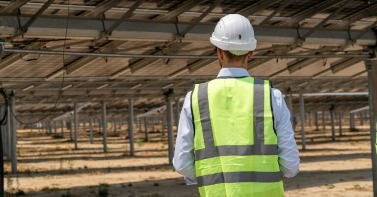 Solar engineer inspecting photovoltaic modules for performance and product warranty evaluation